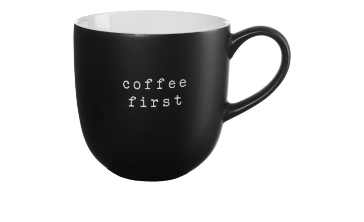 Der Henkelbecher Hey! 350 ml ist ein schwarzer Keramikbecher mit "coffee first" in weiß, ideal für eine stilvolle Dekoration.