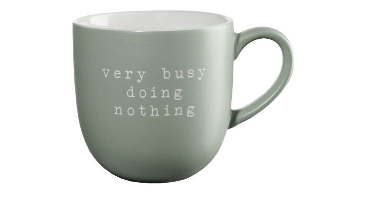 Ein hellgrüner Henkelbecher Hey! 350 ml, Ø9cm, mit "very busy doing nothing" in weißer Schreibmaschinenschrift.