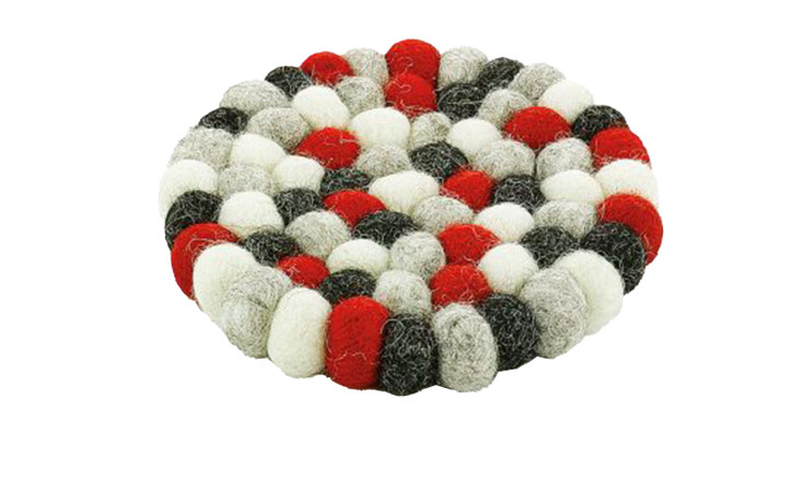 Untersetzer Lana ist ein runder Untersetzer aus roten, schwarzen, weißen und grauen Filzkugeln in einem kreisförmigen Muster.