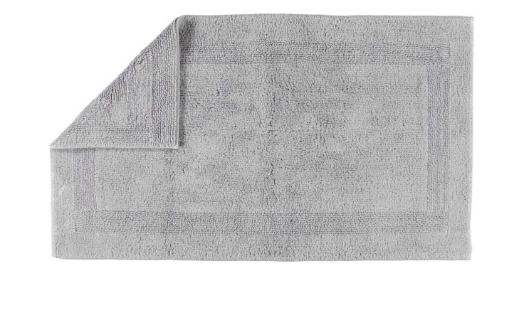 Ein sauber gefalteter Cawö Wende-Badteppich 60 x 100 cm, platinfarben, mit einer umgeschlagenen Ecke auf weißem Grund.