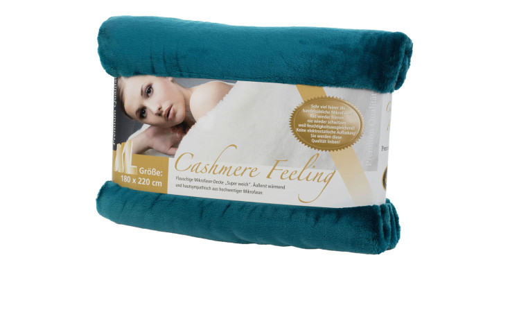 Eine petrolfarbene Gözze Wohndecke Premium Cashmere Feeling 180 x 220 cm, die Verpackung zeigt eine Frau.