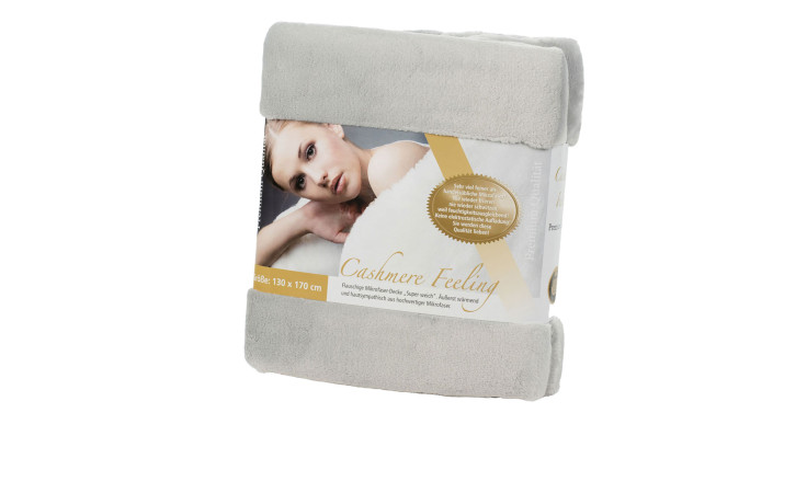 Gefaltete Gözze Wohndecke Premium Cashmere Feeling 130x170cm mit Etikett und Foto einer in Decke eingewickelten Frau auf der Verpackung.