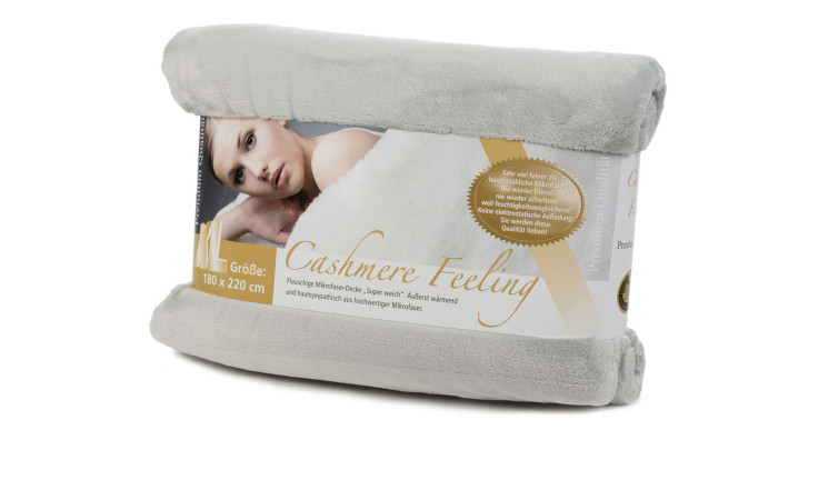 Eine gefaltete hellgraue Gözze Wohndecke Premium Cashmere Feeling 180x220cm, Anhänger zeigt Frau unter einer silbernen Decke.