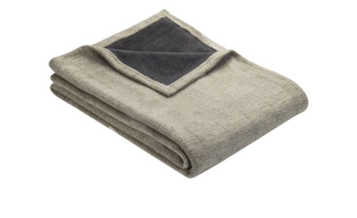 Eine gefaltete Heimdecke 150 x 200 cm hellgrau mit einer dunkelgrauen Ecke auf weißem Hintergrund.