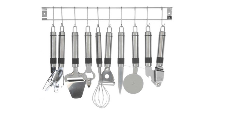Das Küchenhelfer-Set 9 tlg. enthält Edelstahl-Utensilien wie Schneebesen, Pizzaschneider und Sparschäler auf einem Wandhalter.