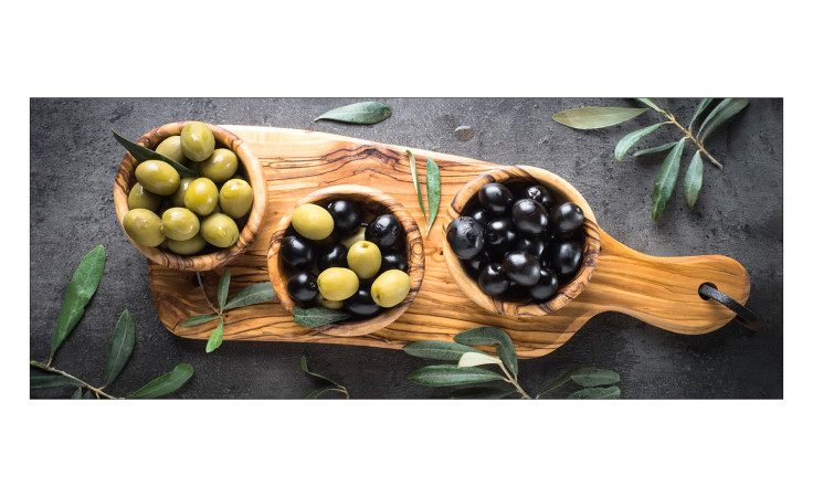Glasbild Mediterrean Food 30 x 80 cm von Pro-Art zeigt bunte Oliven in Schalen mit Olivenzweigen als Dekor.