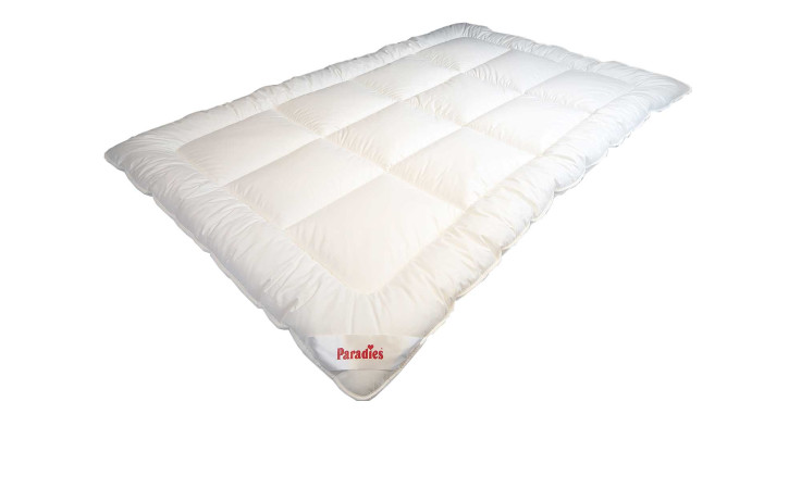 Eine flauschige weiße Paradies Winterbettdecke Nima Bio 135x200cm mit abgesteppten Quadraten, rotem Etikett, isoliert auf weiß.