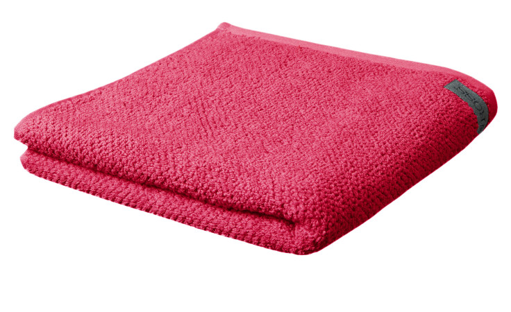 Ein gefaltetes Ross Handtuch BIO Selection 50 x 100 cm mit strukturierter Oberfläche und dunklem Anhänger, isoliert auf weiß.