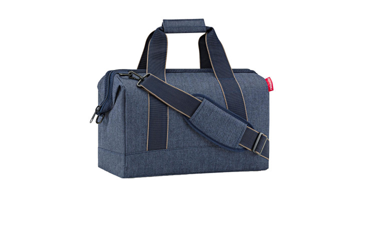 Die Reisenthel Reisetasche Allrounder M in dunkelblauem Fischgrätmuster ist aus recyceltem Polyester mit dunklen Griffen gefertigt.