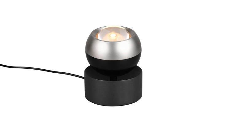 Die Trio LED-Tischleuchte Orbit 10 cm ist eine moderne schwarz-silberne Leuchte mit rundem Sockel und schwarzem Stromkabel.