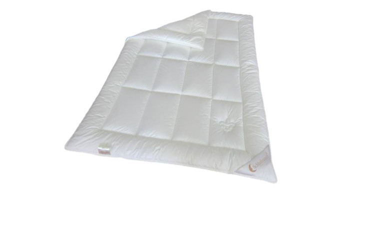 Die Ganzjahresdecke Lilly ist eine weiße, rechteckige 155x200 cm große Bettdecke mit einem dezent gestickten Logo und einer gefalteten Ecke.