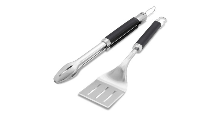 Weber Grillbesteck 2-teilig: Zange und Pfannenwender mit schwarzen Griffen nebeneinander auf weißem Grund.