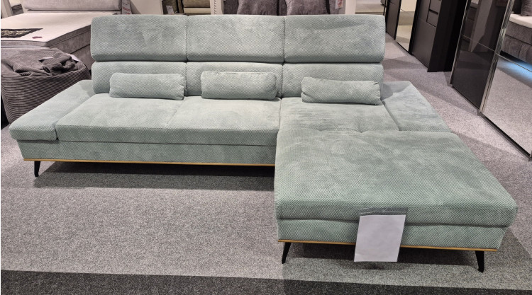 Wohnlandschaft „Malie“ aus dem Stoff „Onega Aqua“ mit Federkernpolsterung, L-förmig, auf einem mit Teppich ausgelegten Ausstellungsraum-Boden.