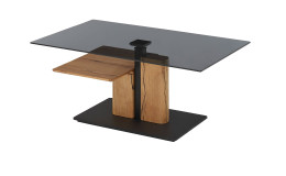 Couchtisch Dallas mit einem massiven Block-Gestell aus Eiche und einer grauen Tischplatte aus Glas schräg von der Seite abgebildet.
