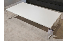 Couchtisch „Toscana“ aus weißem, seidenmattem Lack mit pulverbeschichteten, reinweißen Beinen neben einem dunkelgrauen Sofa.