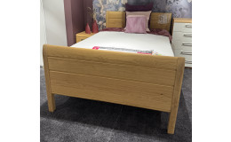 Bettgarnitur „MONDO Comfort Plus“ 120 x 200 cm, weiße Bettwäsche, lila Kissen, Nachttisch, Vasen in einem mit Teppichboden ausgelegten Zimmer.