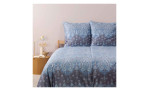 Blaue und graue Paisley Satin-Bettwäsche Isolabella 155x220 cm von Bassetti auf dem Bett mit Nachttisch, Lampe und Buch daneben.