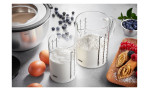 Das GEFU Messbecher-Set 2-tlg. Meti mit Milch, Mehl, Eiern, Blaubeeren und Pfannkuchen auf dem Küchentisch.