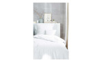 Minimalistisches Schlafzimmer mit Renforce-Bettwäsche Stone Washed, Kissen, einer Vase mit Zweigen und Kunst auf einem weißen Regal.