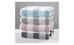 Vier gefaltete Cawö Handtücher Karo 50 x 100 cm in Pastellblau, Taupe, Rosa und Anthrazit auf weißer Oberfläche.