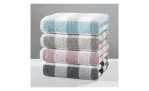 Vier flauschige, mehrfarbige Cawö Handtücher Karo 50x100 cm in blau, beige, rosa und grau auf einem neutralen Hintergrund gestapelt.