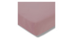 Eine Nahaufnahme eines Estella Jersey-Spannbettlakens 100 x 200 cm in rosa, das eine Matratzenecke vor weißem Hintergrund bedeckt.