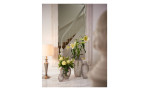 Die Leonardo Vase Poesia 40 cm in grau hält gelbe und weiße Blumen durch eine Lampe und Spiegel auf einem Marmortisch.