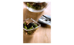 Eine Leonardo Schale Piazza 12 cm Glasschale mit Salat steht auf einem Holztisch neben Gabeln und einer größeren Salatschüssel.