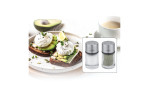 Avocado-Toast mit pochierten Eiern, Glas-Kaffeetasse und Küchenprofi Pfeffer-/Salzstreuer auf der Seite.