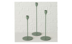 Drei Boltze Kerzenleuchter Malte 23 cm aus grünem Metall auf weißer Fläche vor einer weißen Backsteinwand.