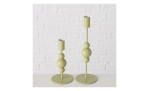Zwei hellgelbe Kerzenleuchter Akesha 17 cm mit gestapeltem Kugeldesign stehen auf einer weißen Fläche an einer Ziegelwand.