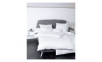Mako-Satin Kissenbezug Colors, in der Größe 80 x 80 cm und in einer Farbausführung weiß, auf einem Bett bezogen mit der passenden Bettwäsche und anderen Kissen
