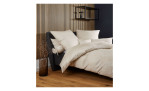 Ein modernes Schlafzimmer mit Mako-Satin-Bettwäsche Milano, dunklem Bettgestell, Holzlattenwand, schwarzem Regal und Glasvase.