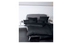 Mako-Satin Kissenbezug Colors in der Größe 40 x 40 cm und in der Farbausführung schwarz, auf einem bett bezogen mit der passenden Bettwäsche und weiteren Kissen