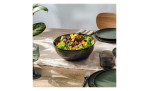 Ein frischer Salat in der Villeroy & Boch Salat-/Servierschüssel Lave vert auf einem Tisch mit Tellern, Gläsern und Besteck.