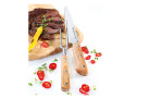 Geschnittenes Steak mit gelber Paprika, Tomaten und Tranchierbesteck 2-tlg. auf einem Holzbrett.