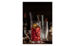 Ein transparenter roter Cocktail mit Eis und Zitrone in einem Zwiesel Glas Longdrinkglas Show 4er, Ø 7 cm, auf einem schummrigen Bartresen.
