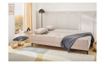 Das Schlafsofa „Feye“ mit Kissen und grauer Decke; Höhe, Breite und Tiefe sorgen für Ausgewogenheit in dem hellen Raum.