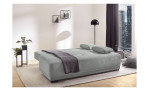 Schlafsofa „Delia“ mit Kissen und Decke sowie Pflanzen und Regalen; passt perfekt in moderne, urbane Wohnräume.