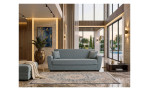 Modernes Wohnzimmer mit einem blauen 3-Sitzer-Sofa „Aiden“, einem gemusterten Teppich, großen Fenstern und Blick auf den Pool draußen.